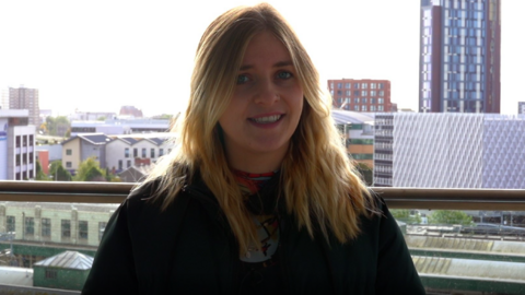 Woman looking into the camera with a city skyline in the background