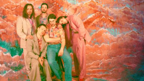 Press image of Cousin Kula - five men in loose-fitting suits in a colourful backround