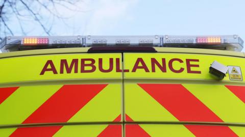 A stock image of the back of an ambulance with the lights flashing.