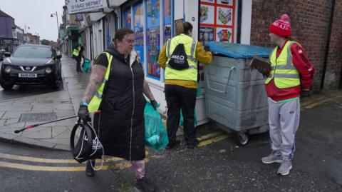 Volunteers clear debris on Murray Street in Hartlepool following a violent protest on Wednesday evening