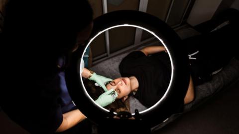 A woman lying on a bed having a beauty treatment. 