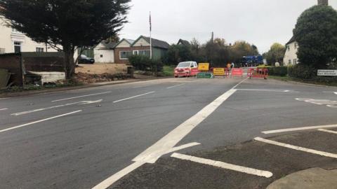 A road junction where the road ahead has been blocked by barriers and road signs.