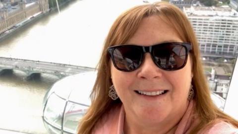 Wendy Pinch is seen in a selfie taken from high up in the London Eye. Landmarks such as the Palace of Westminster and the River Thames are visible in the background.