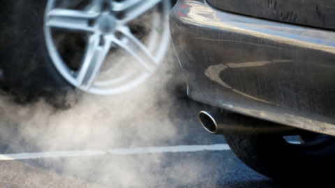 A picture of a car exhaust pipe, with a cloud of petrol or diesel coming out the back.