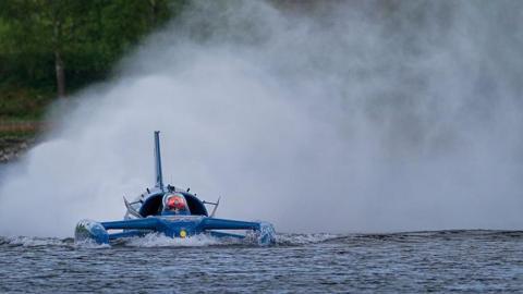 Spray rises from the back of Bluebird - a craft looking like a cross between a boat and a plane - as it runs on Coniston Water.