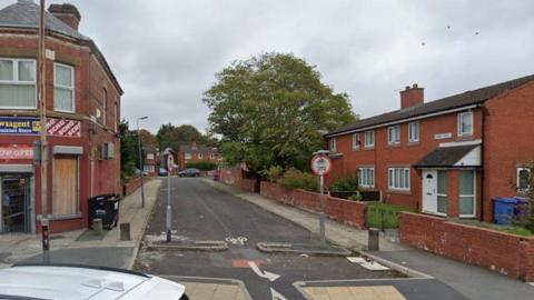 A corner newsagents shop is on the left at the entrance to Thames Street with two semi-detached homes on the right and some other houses at the end of the street.