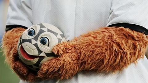 Smiley face on a football, held by a person in a bear mascot costume