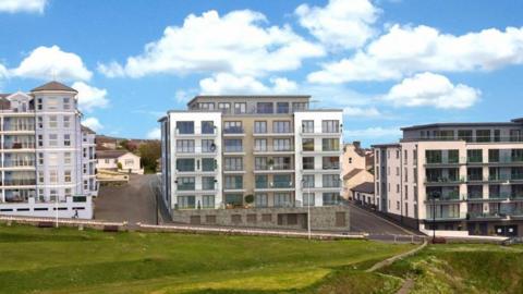 A CGI visualisation of a modern block of flats on a promenade street, with two existing blocks either side. It has a grey and white facade, with glass balconies. A grassy sloping area is in the foreground, with blue skies above.