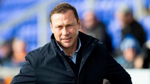 Duncan Ferguson in a football stadium with fans in the background.