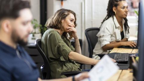 Stressed businesswoman sitting in front of desktop PC at office