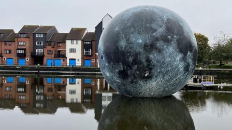 The Fallen Moon display, which is a large moon based of NASA data, floating on water in Bridgwater's docks