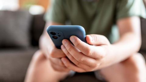 A young person uses their blue cased smart phone