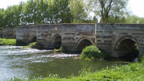 A river flows under a bridge with four arches