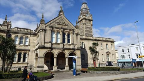 Entrance to Weston-super-Mare Town Hall with person walking past pushing someone in a wheelchair,