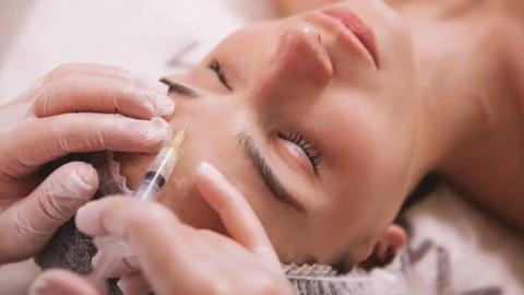 A generic image of a procedure, with a piece of equipment on a woman's forehead. She is lying down in the photo and her eyes are closed.