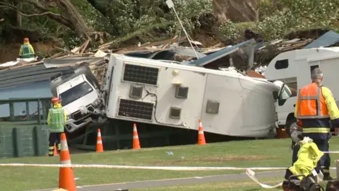 Two camper vans are seen toppled in an area cordoned off by rescue workers
