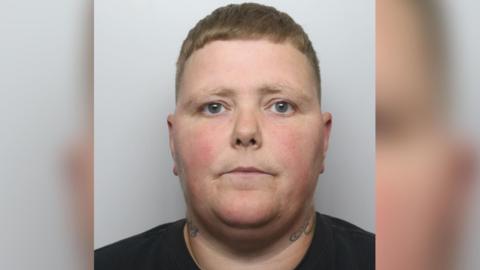 A mugshot of Aimee Hodgkinson-Hedgecox, a woman with short brown hair and tattoos on both sides of her neck, wearing a black top.