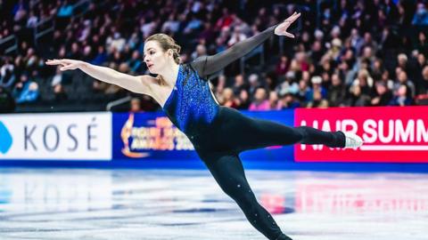 Kristen Spours with her arms stretched out wide as she skates on one leg with the other stretched behind her during a routine at the World Championships in March 2025