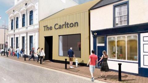 Artist's impression of the new entrance and box office to the Carlton Cinema. The single story building, clad in yellow material with a large square window, is labelled The Carlton. To the left is the high white 18302 building, and a low rise building to the left. People are walking on the street in front of it. 