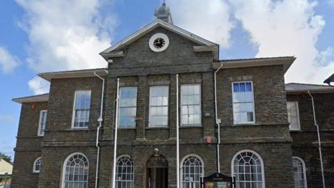 Aberaeron library is a large stone building of two storeys with several windows and a clock on the front at the top