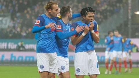 Holstein Kiel's Shuto Machino (R) celebrates after scoring the opening goal against Borussia Dortmund in the Bundesliga