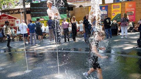 Children splash through the cooling waters of the fountains in Leicester Square