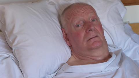 Jerry Ward, lying in a bed at his home. His head and shoulders are in frame. He is bald and wearing a white top.