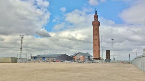 A long view of the Grimsby Dock Tower across an open piece of land in the docks