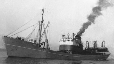 A black and white photograph of the trawler at sea - smoke billowing from its chimney.