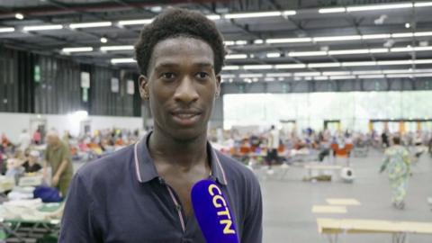 Jean Philippe, an evacuee, stands in front of a microphone