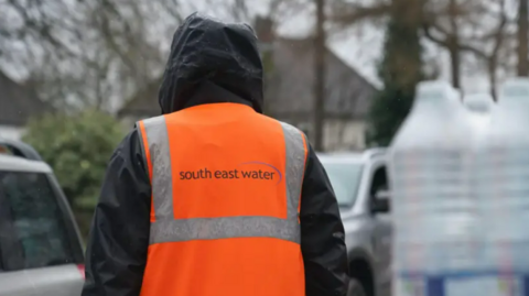 Person stands in the rain with a South East Water high vis jacket