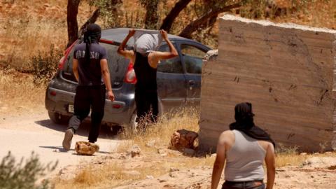 Palestinian men with their heads covered clash with Israeli forces in the village of al-Mughayyir, near Ramallah, in the Israeli-occupied West Bank (11 July 2026)