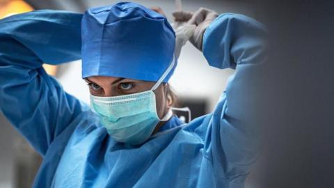 Female clinician wearing PPE in an operating theatre