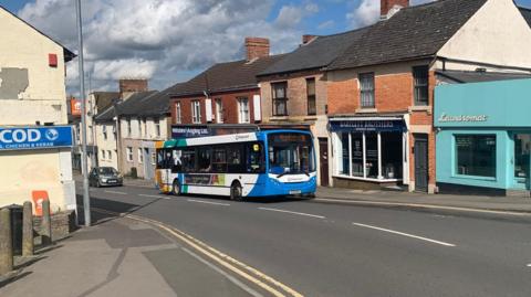 The number 9 bus crests Victoria Hill in Swindon on its way to Wroughton. Various businesses can be seen in the background.