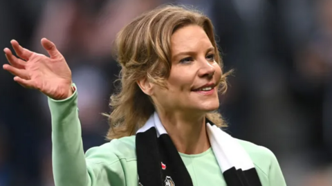 Amanda Staveley waving while wearing a Newcastle scarf