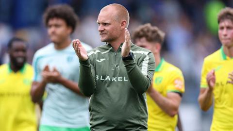 Liam Manning applauds the away fans with his players after beating Portsmouth