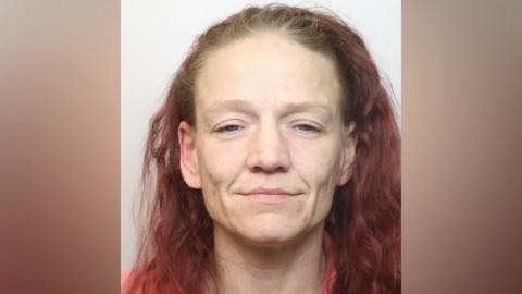 Mugshot of Lisa Kelly, a 40-year-old white woman with dyed-red wavy hair. 