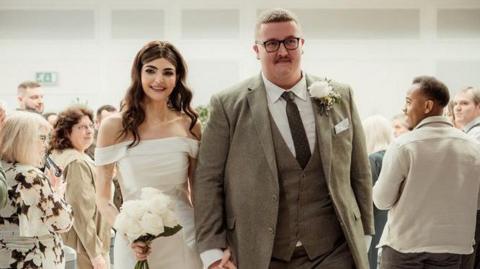 A couple at their wedding walking down the aisle past friends and family 