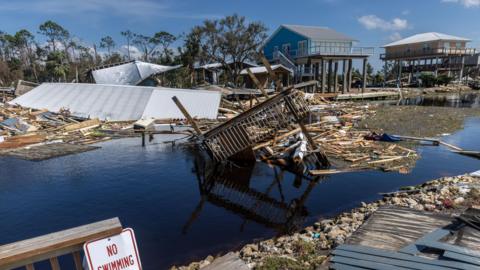 Collapsed buildings lie in flood water