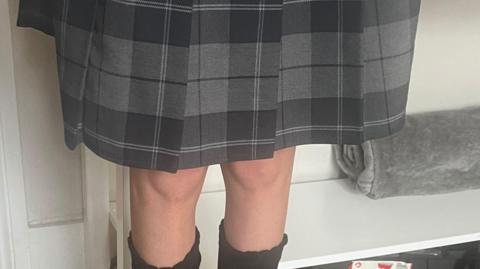 Picture of a plaid skirt at kneecap length.