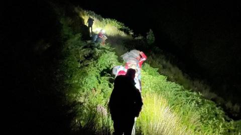 Rescue volunteers making their way up a hillside in the dark