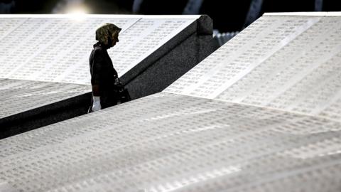 A woman walks through a memorial to the victims of the Srebrenica massacre