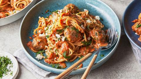 A plate of spaghetti and meatballs with cherry tomato sauce.