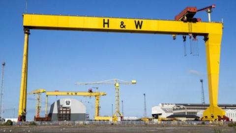 A yellow Harland and Wolff crane is in the foreground, in the background the second crane can be seen, they are both set against a blue sky.