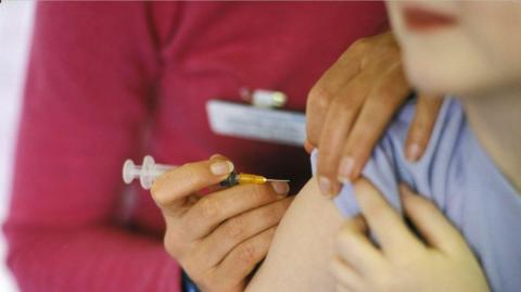 A close-up image of a person about to have a needle placed into their arm.
