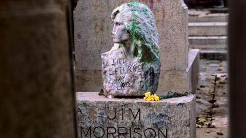 The bust of Jim Morrison, covered with graffiti, at his grave in Paris's famous Père-Lachaise cemetery