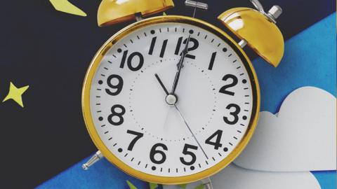 Image of a clock pointing to 10 o'clock, on a background that is split diagonally is half, one half showing a day scene, the other half showing night