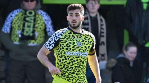 Jordan Moore-Taylor running on the pitch with the ball at his foot during a match
