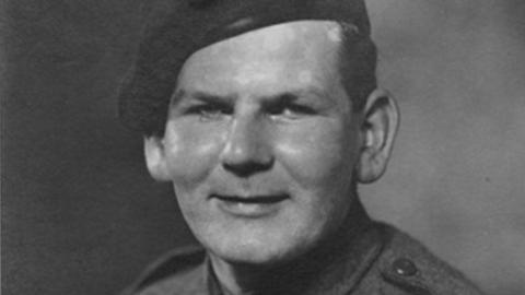 A black and white photo of Alfred Edward Thomas (Eddie) Annetts in Army uniform during World War Two. He has a beret on his head and the shoulders of his uniform can be glimpsed. He has short dark hair and is smiling at the camera.