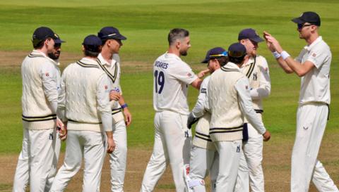 Chris Woakes receives the congratulations of his Warwickshire team-mates after taking a Sussex wicket at Edgbaston